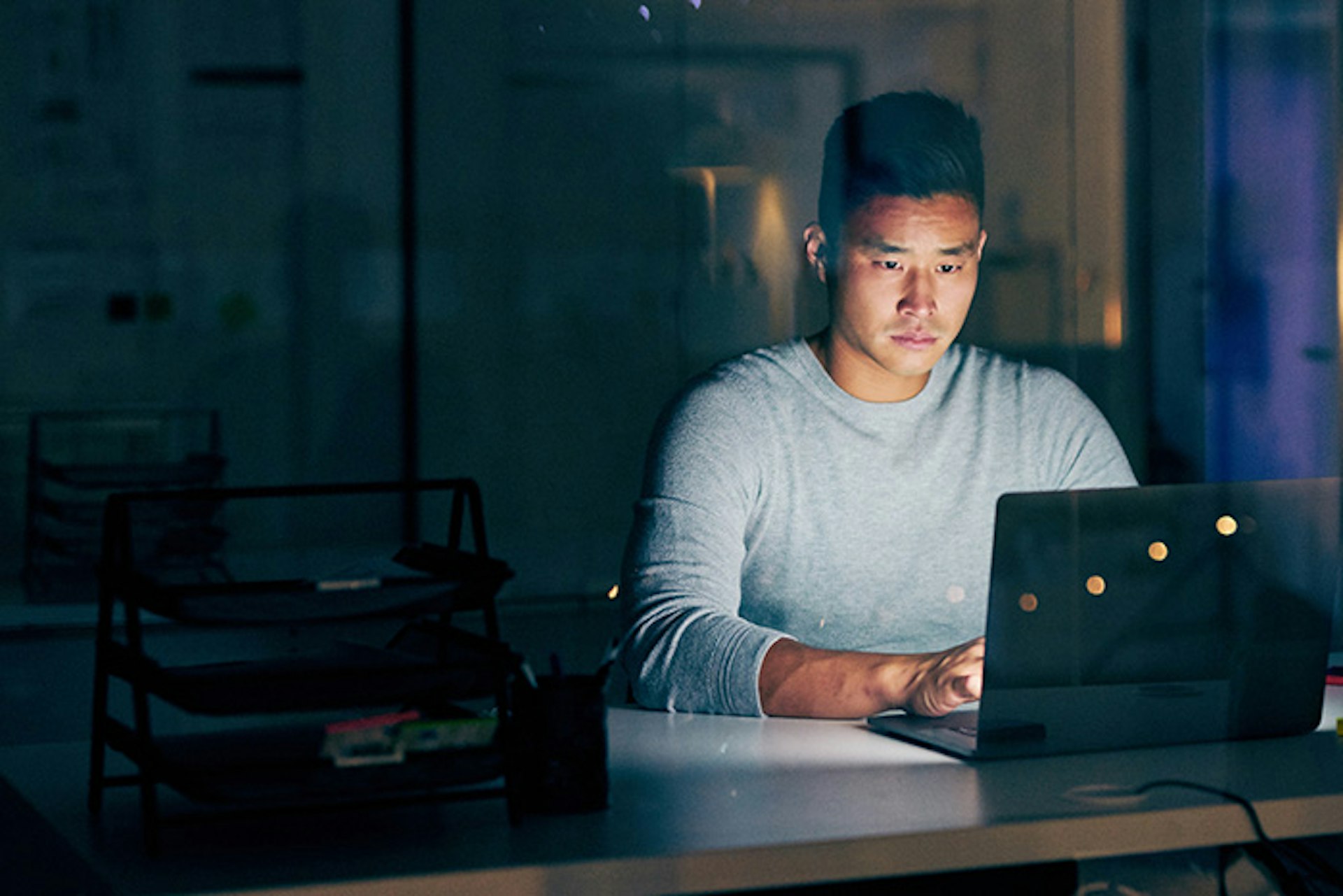 Hombre iluminado por un ordenador portátil en una habitación oscura